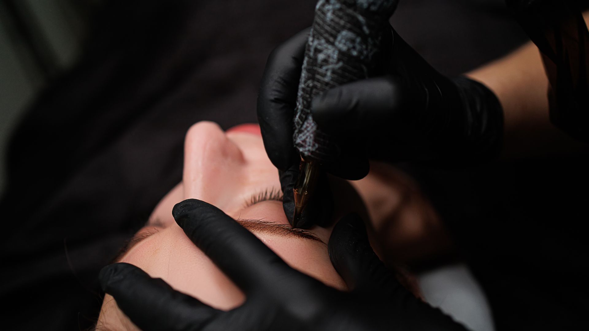 A woman getting a permanent tattoo on her forehead